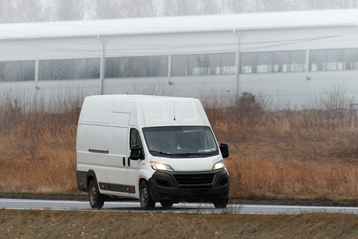 A white van with a blank wrap for your business branding and delivery service. Isolated mockup of a commercial vehicle on the road.