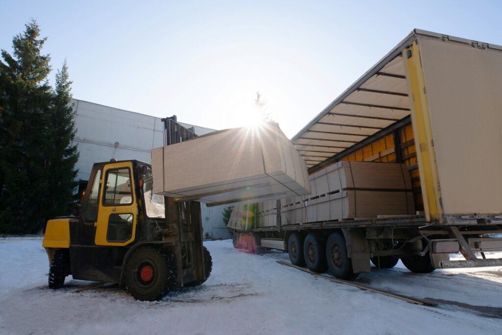 forklift load chipboard panels from truck on large furniture production plant - winter nature