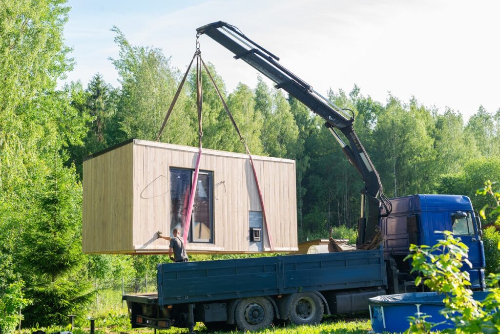 Loading the finished frame building onto the site using a machine crane.